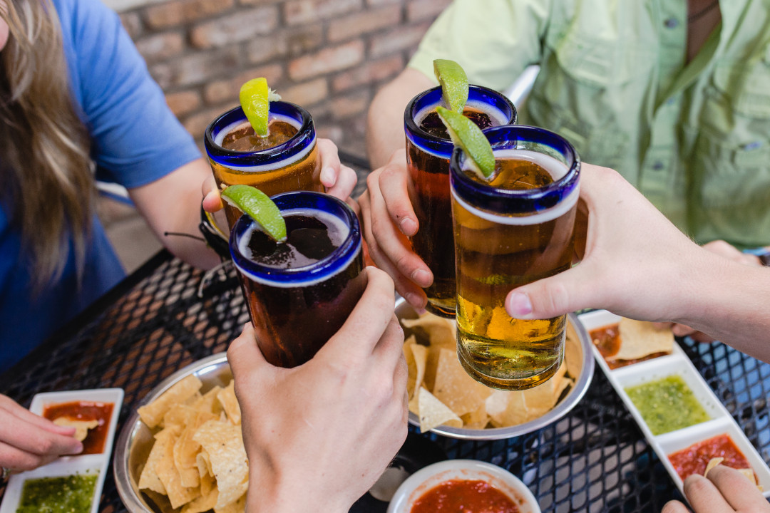 Four hands holding draft beer glasses.